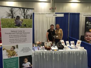 Two middle-aged white women smiling at an exhibit booth.